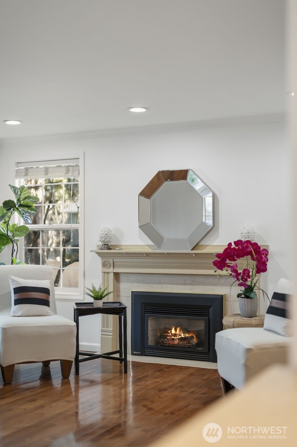 The warm gas fireplace creates a cozy focal point in the living room, surrounded by beautiful hardwood floors and natural light.