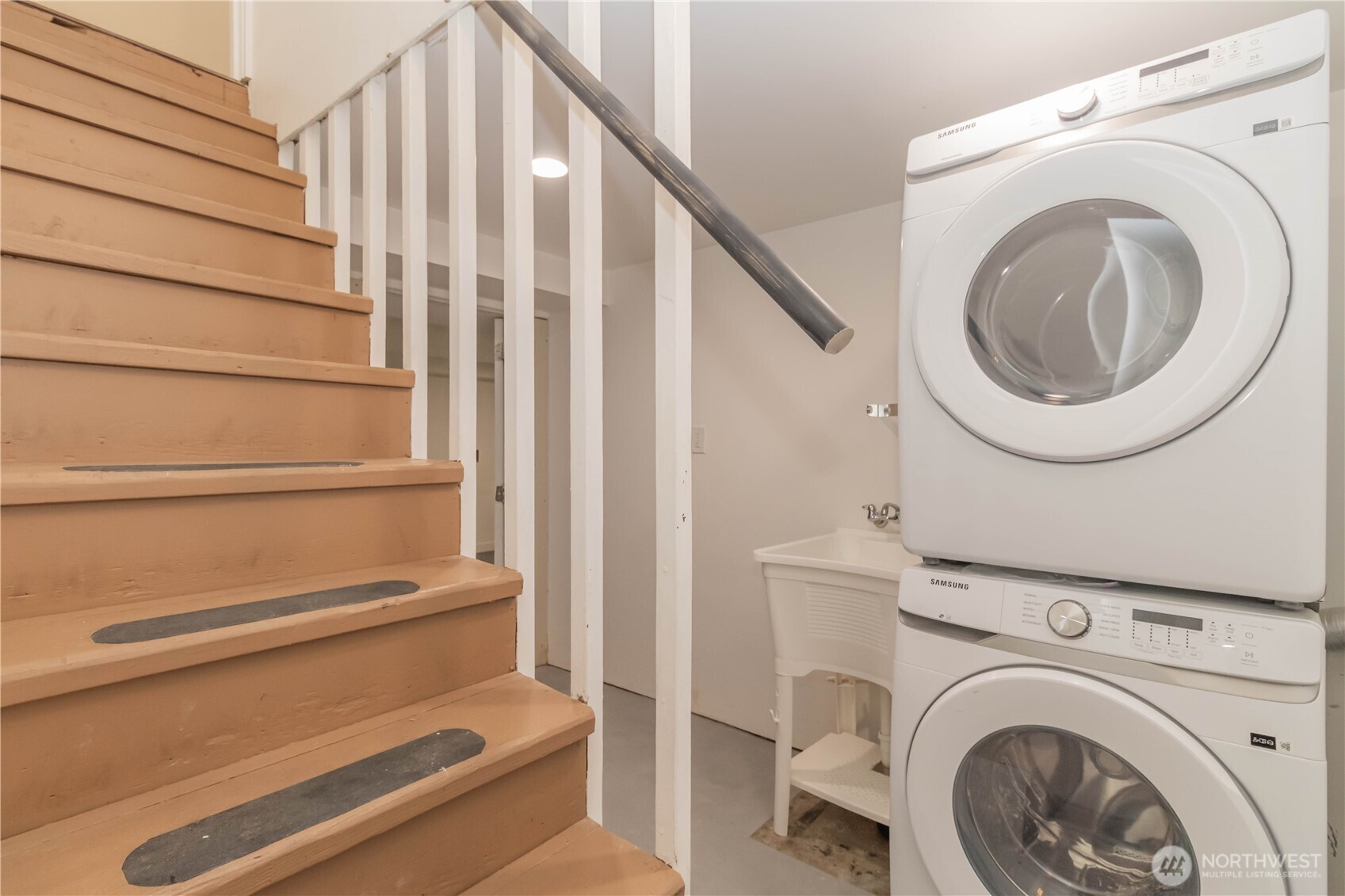 Stairs to basement with laundry and utility sink