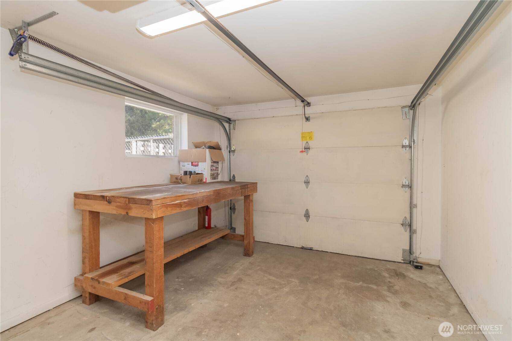 Unfinished shop space with rolling garage door for all your lawn storage, green thumb projects or crafting needs