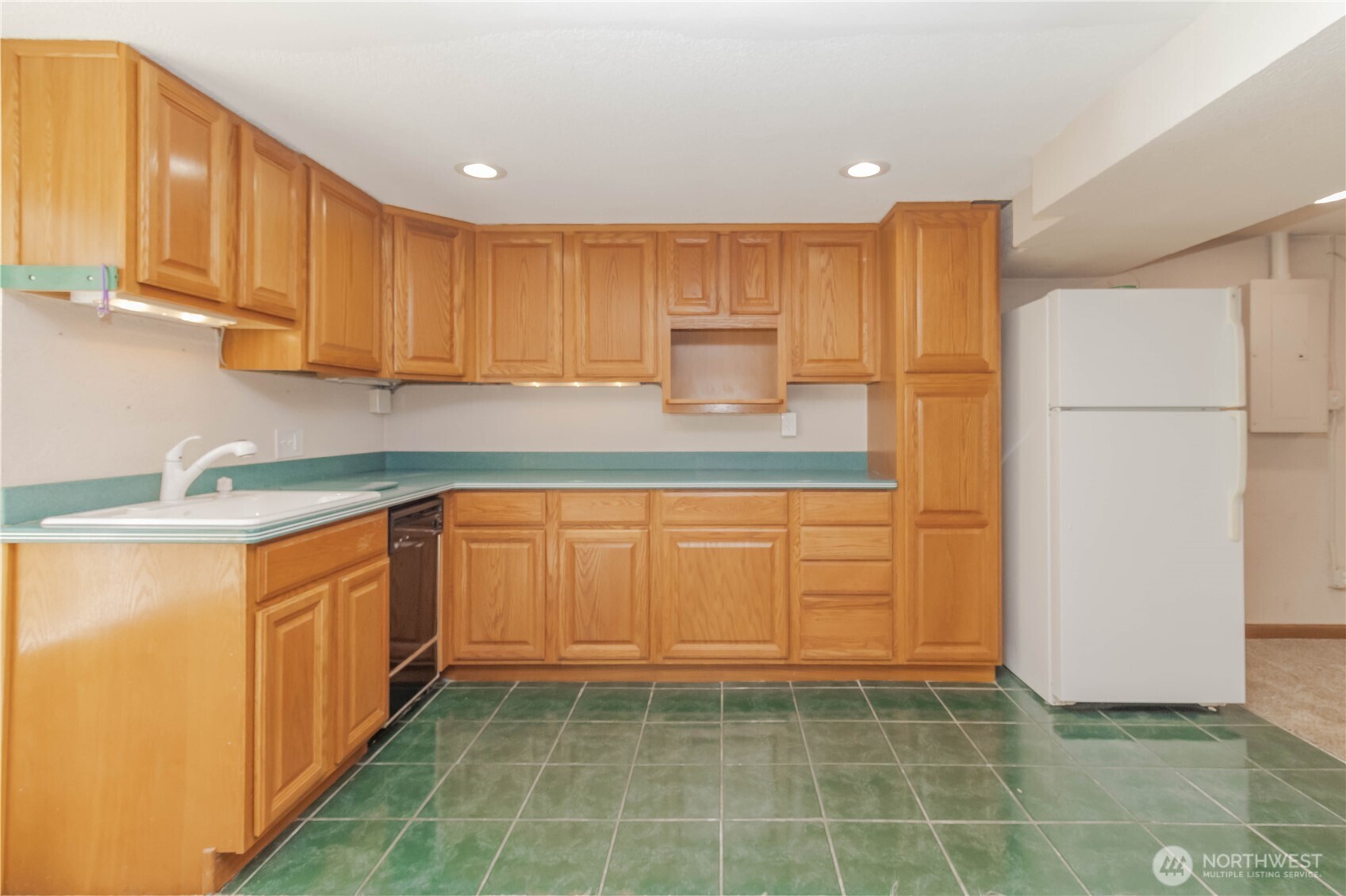 Basement kitchen area has tile flooring, sink, dishwasher and fridge, no heating element