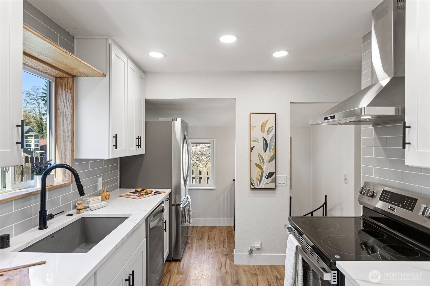 The full run: sink to range, quartz counter to counter — and the spiral staircase in the background is your first hint of what's below.