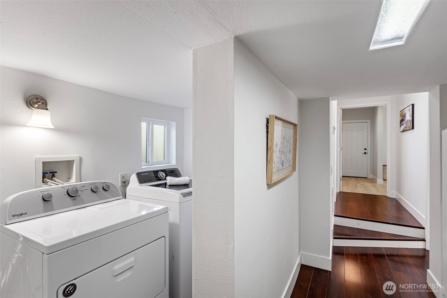 The spiral stair lands here — laundry to the left, daylight corridor straight ahead.
