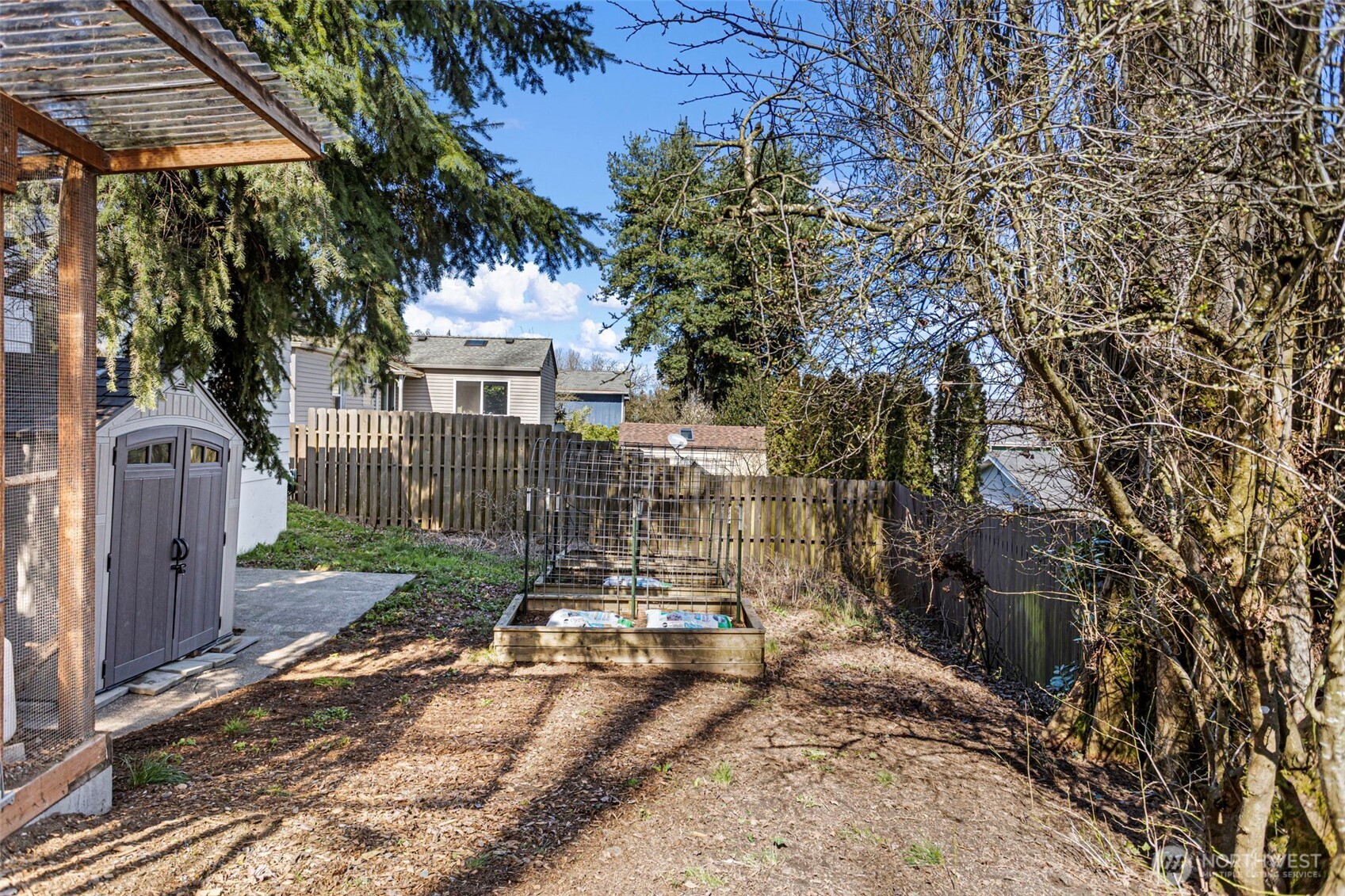 Fresh soil in the raised bed, wire cloche ready, fruit trees just waking up, resin shed to the left. This yard has a head start on the season.