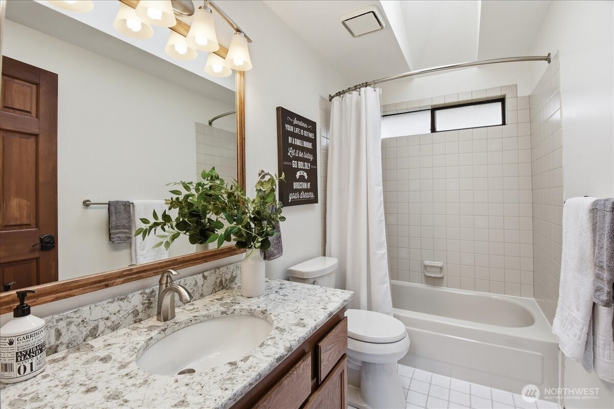 Well-kept guest bath with quartz vanity, tile floors, and a bright, functional layout