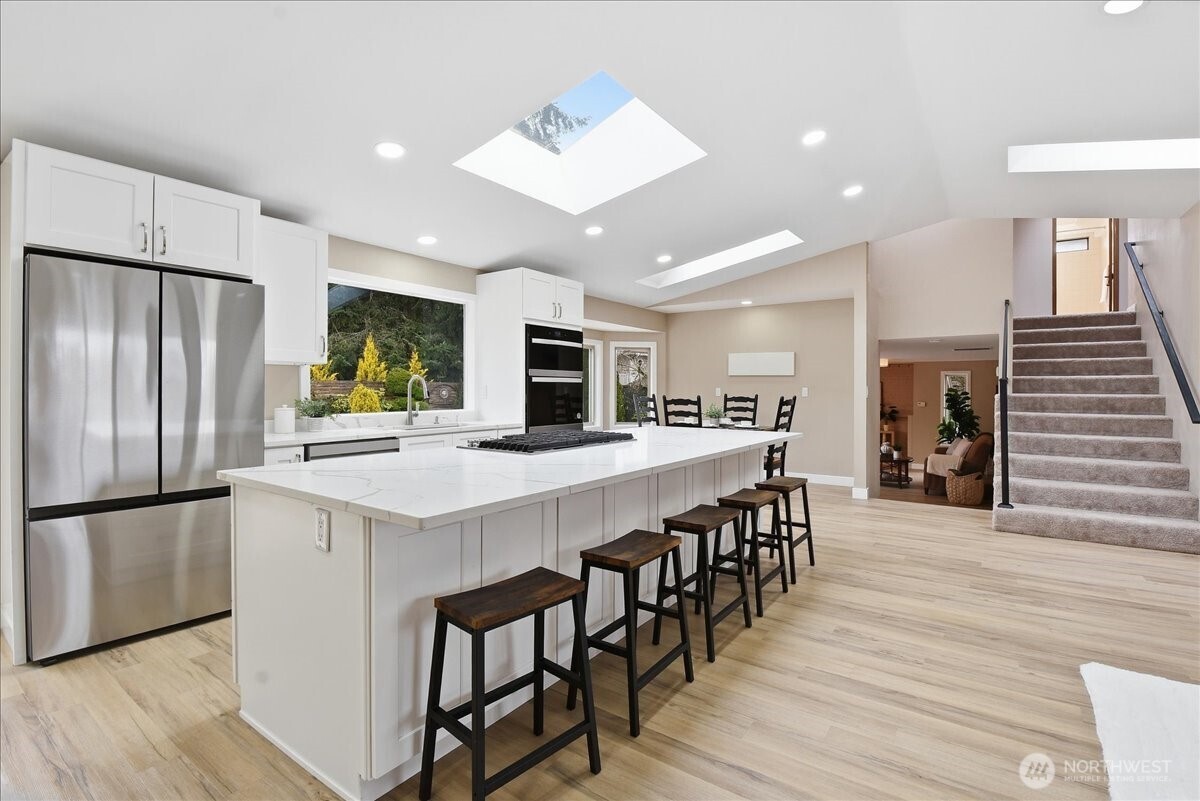 Remodeled kitchen with quartz island, skylights, abundant storage, and seamless connection to dining and living spaces.
