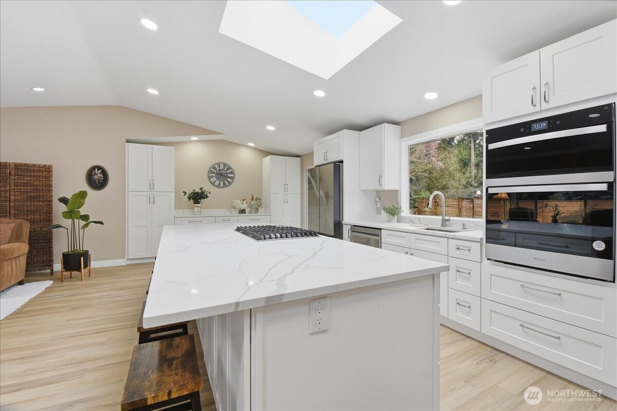 Beautifully remodeled kitchen with oversized quartz island, double ovens, and abundant prep space. Sliding glass door leads to backyard.