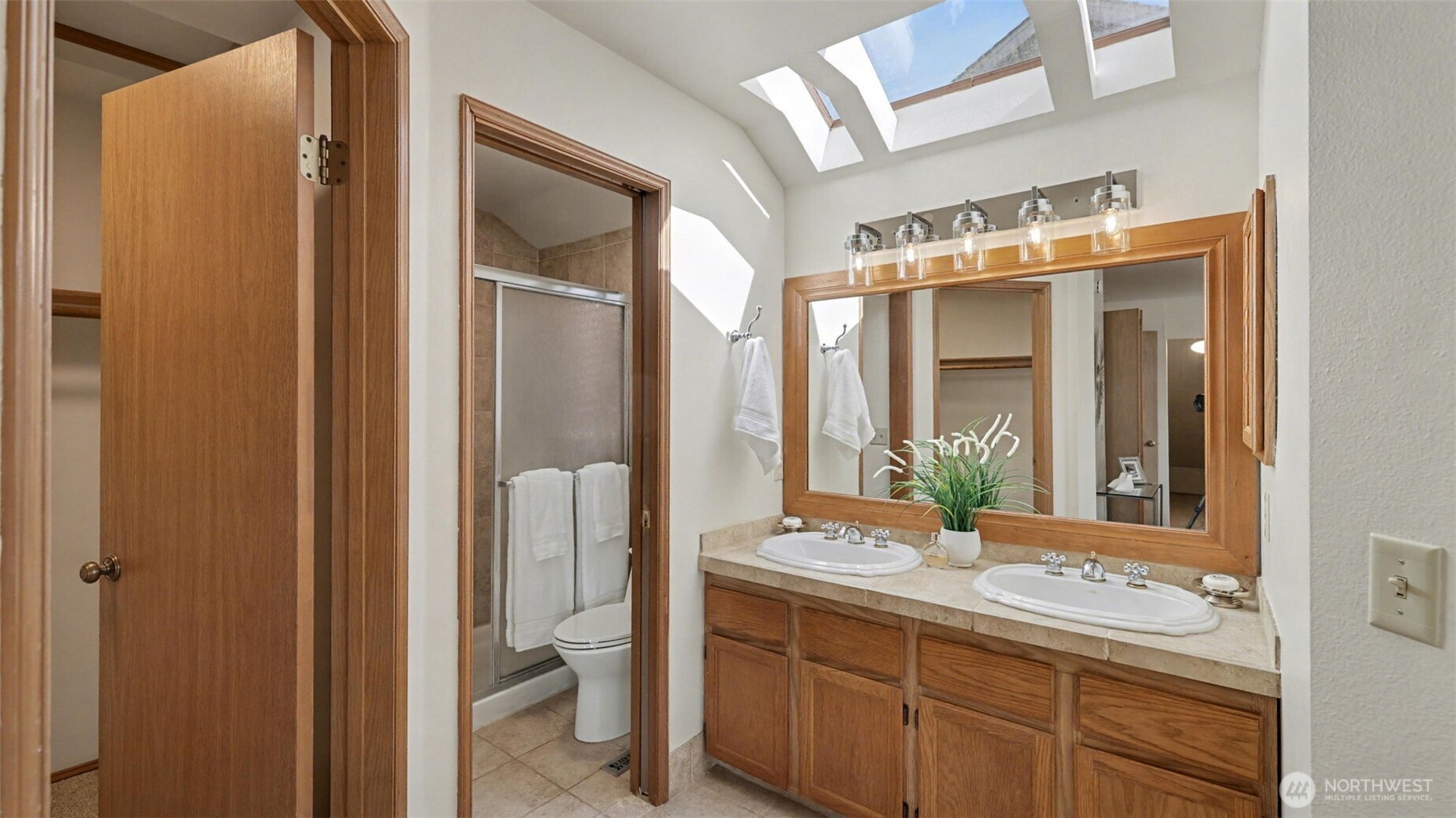 The primary 3/4 bath has tile floors, 2 vanities and skylights.