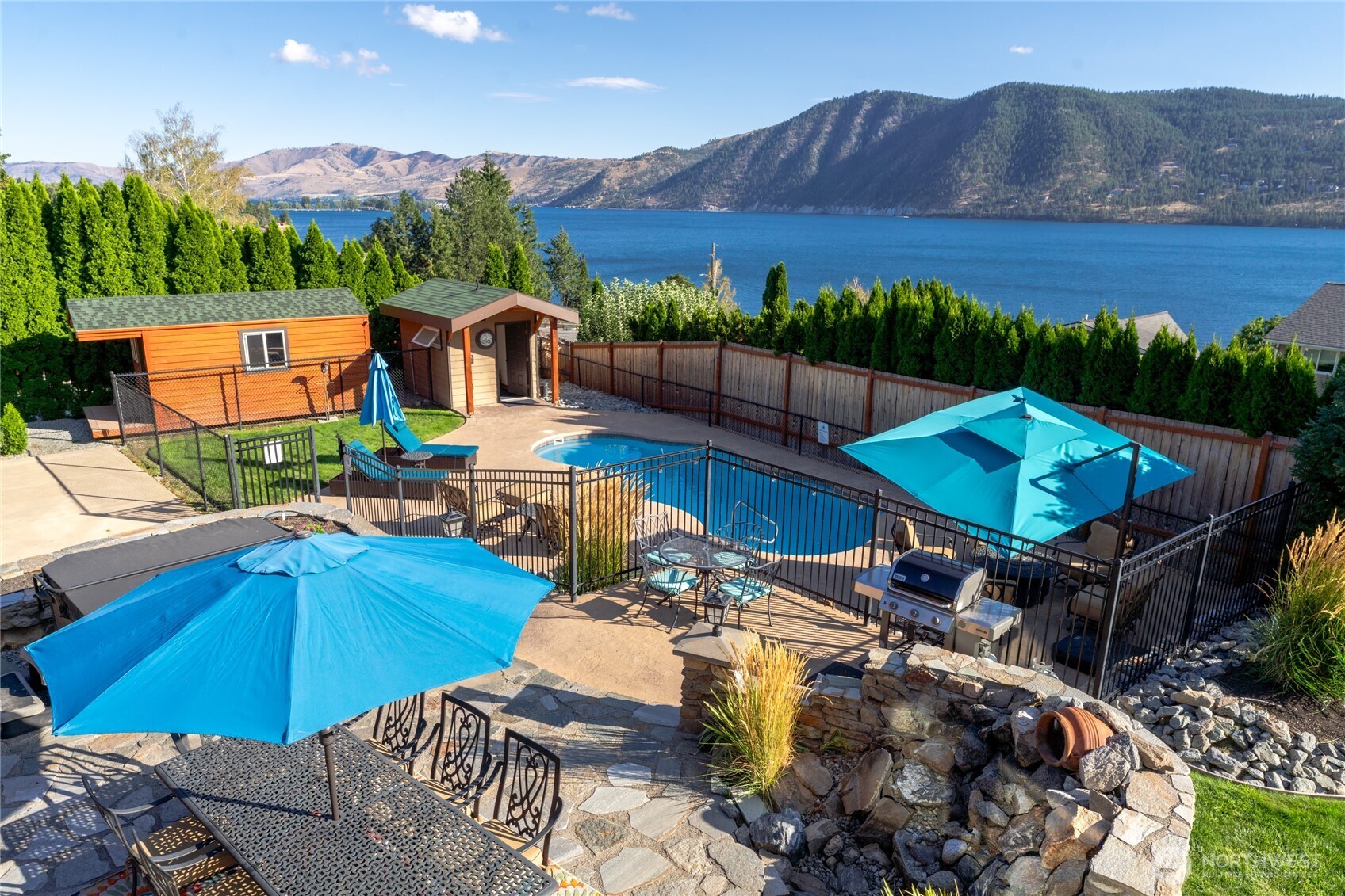Aerial view of outdoor living area w/ pool, hot tub, dining, BBQ and lounge area overlooking Lake Chelan.