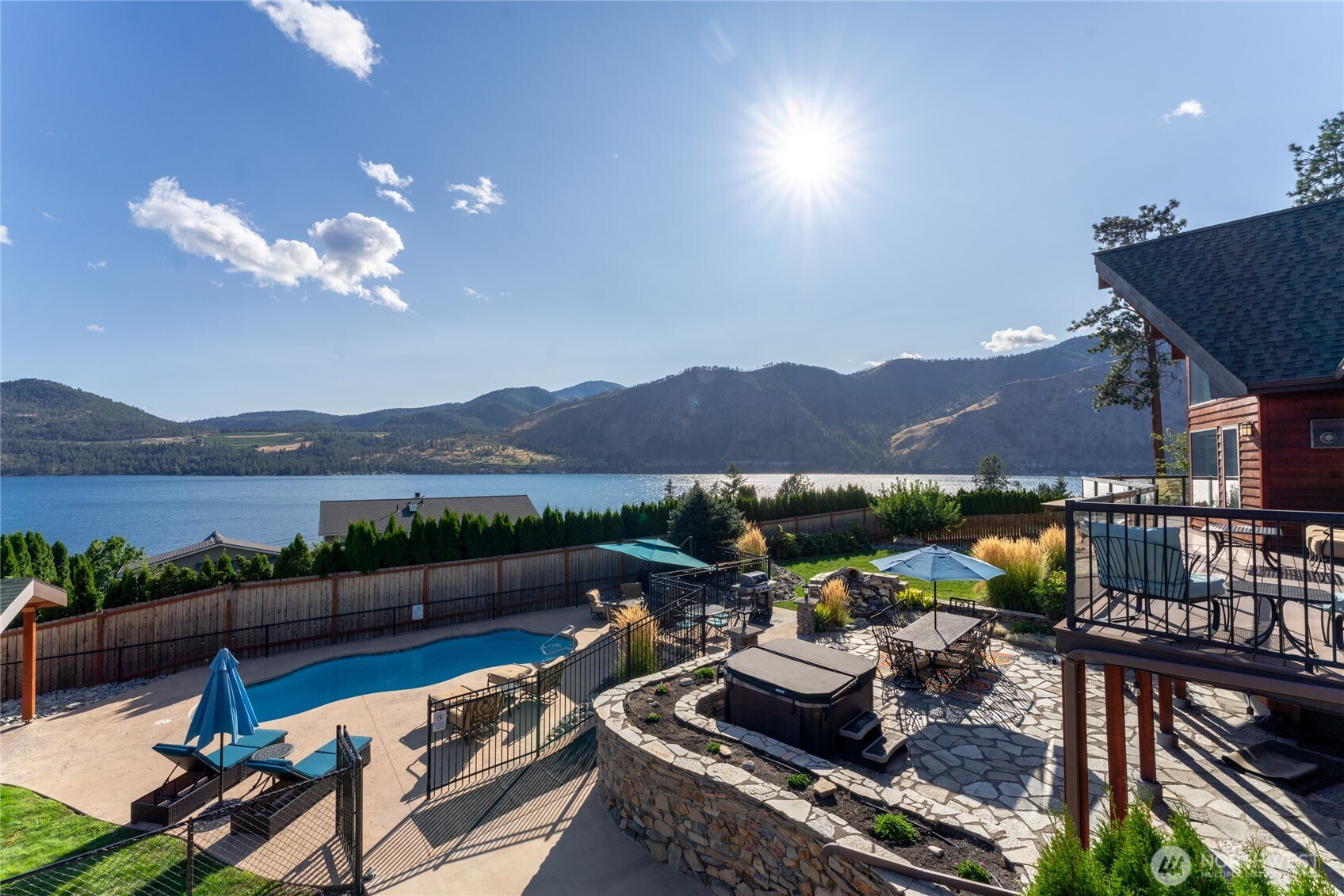 View of outdoor living area w/ pool, hot tub, basketball court, landscaped grounds, dining and lounge areas and view decks overlooking Lake Chelan.