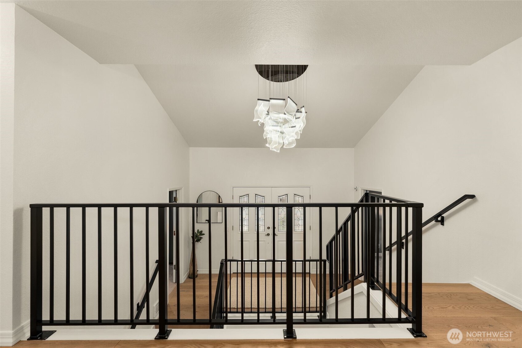 Custom black wrought iron staircase railing complimented by new engineered wide plank Vienna white oak flooring, memorable lighting fixtures and hardware.