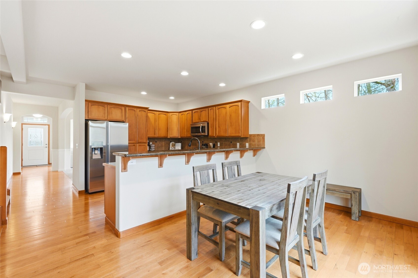 Open-concept kitchen and family room with hardwood floors and greenbelt views