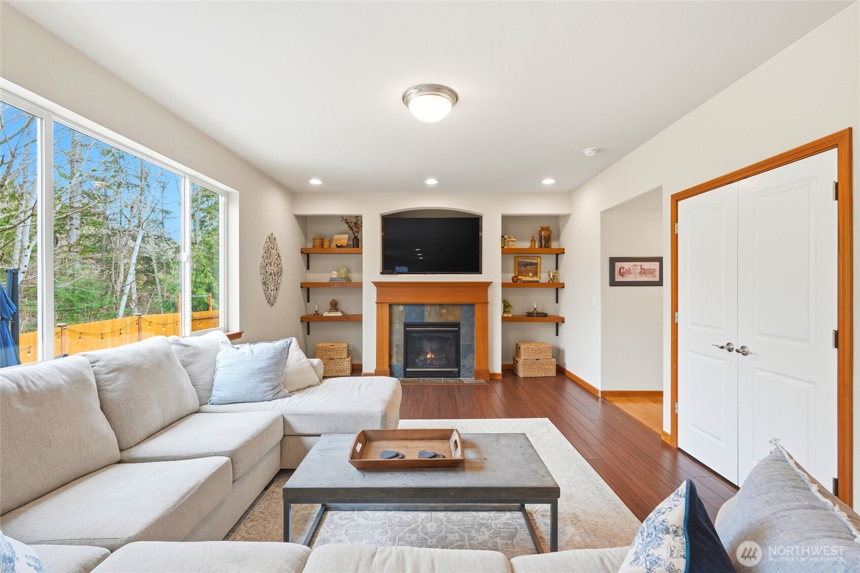 The kitchen opens to a large family room with a gas fireplace and picture windows framing the wooded backdrop.