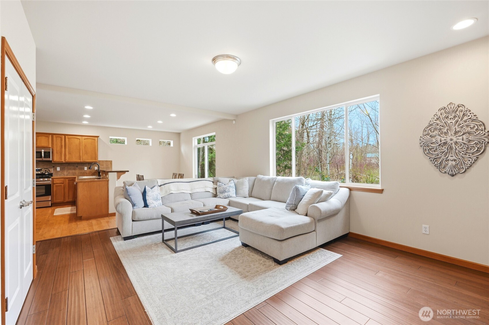 The kitchen opens to a large family room with a gas fireplace and picture windows framing the wooded backdrop.