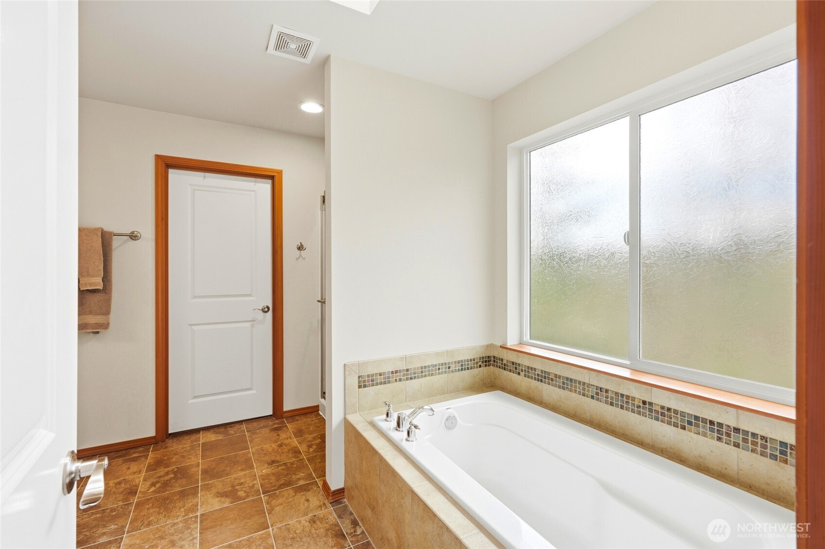 Upstairs, the primary suite overlooks the greenbelt and includes a five-piece bath with soaking tub and a spacious walk-in closet.
