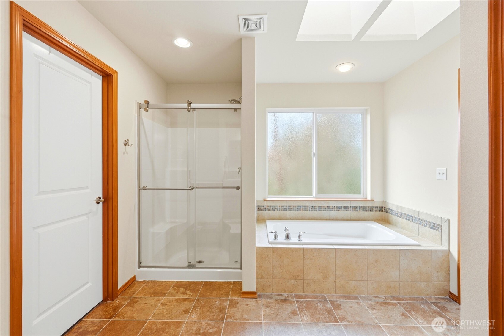 Upstairs, the primary suite overlooks the greenbelt and includes a five-piece bath with soaking tub and a spacious walk-in closet.