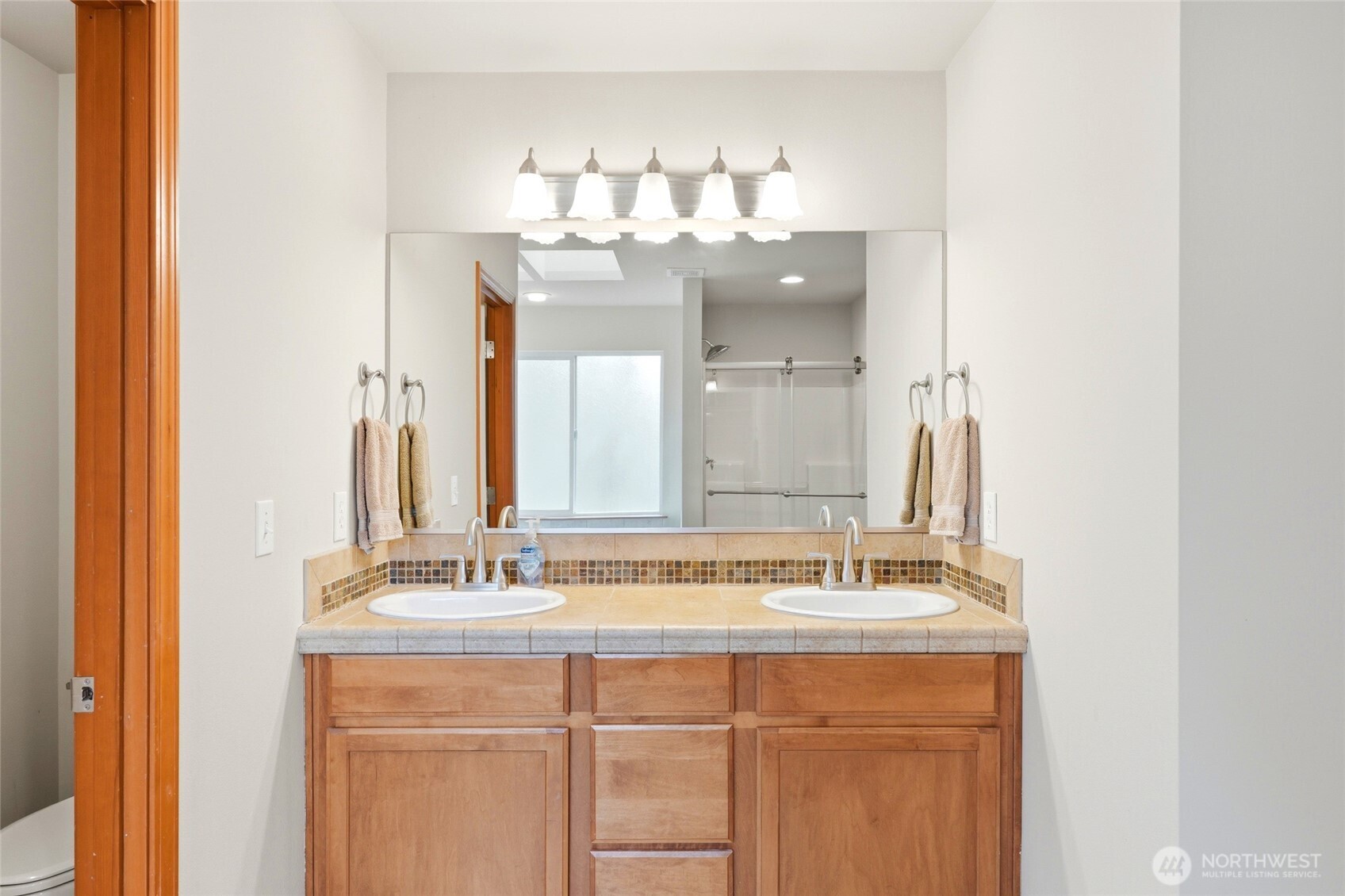 Upstairs, the primary suite overlooks the greenbelt and includes a five-piece bath with soaking tub and a spacious walk-in closet.