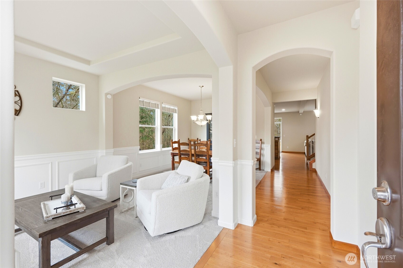 Formal living and dining with wainscoting, arched entries, and hardwood floors