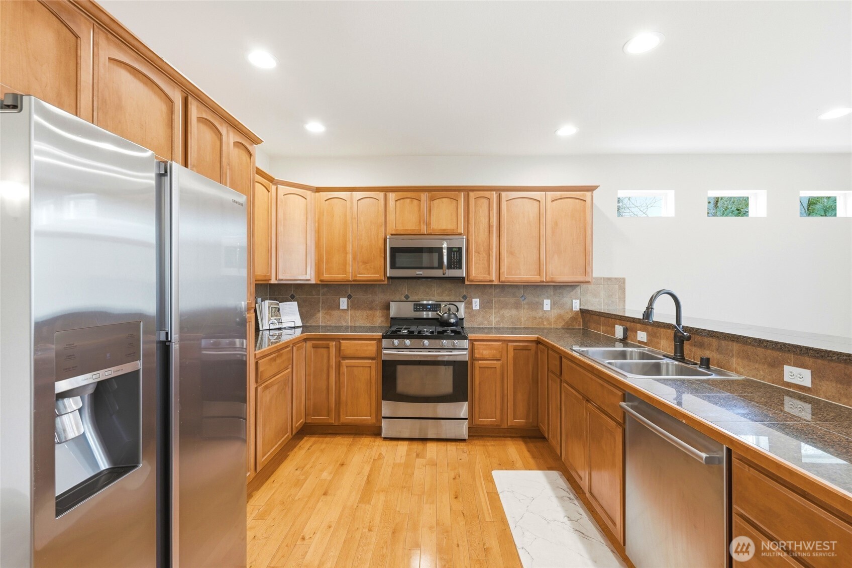 Kitchen featuring gas range, granite counters, and eating bar open to family room