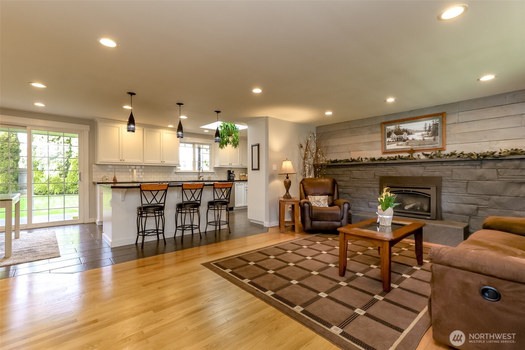 The moment you cross the threshold, the remodeled kitchen shines with pendant lighting and recessed lighting, resting on flawless floors. The back sliding door open to lush, landscaped greenery, creating a seamless indoor-outdoor feel
