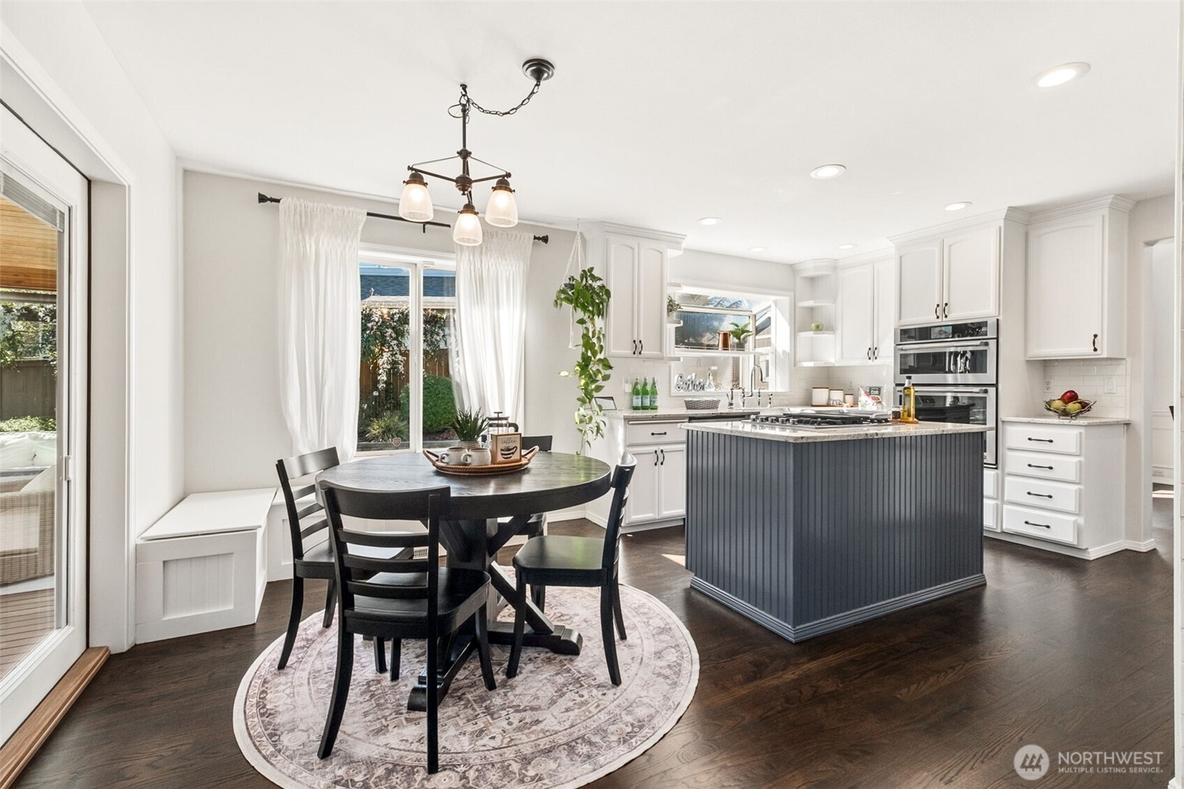 Stunning kitchen featuring a statement island, crisp white cabinetry, and a bright dining nook framed by large windows and natural light.