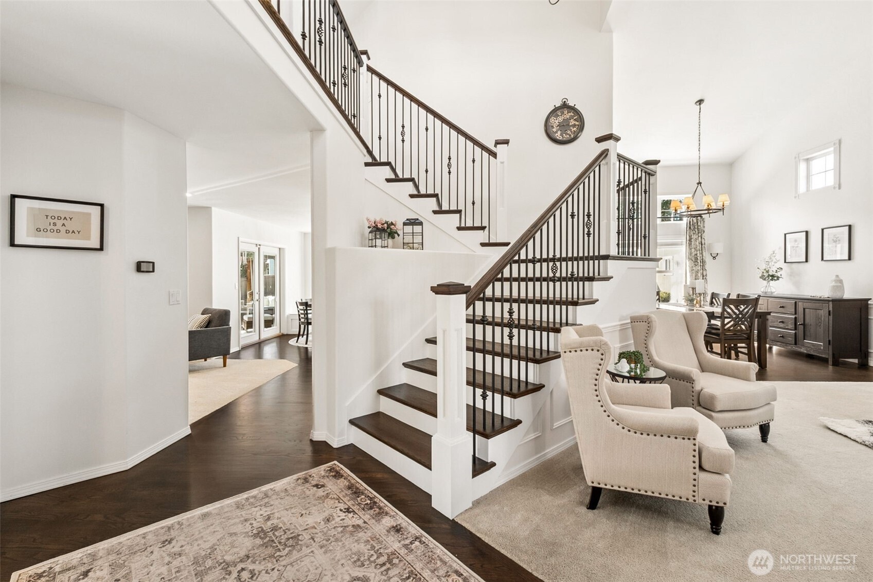 Bright, welcoming entry with soaring ceilings and a beautifully crafted staircase, opening to inviting living and dining spaces