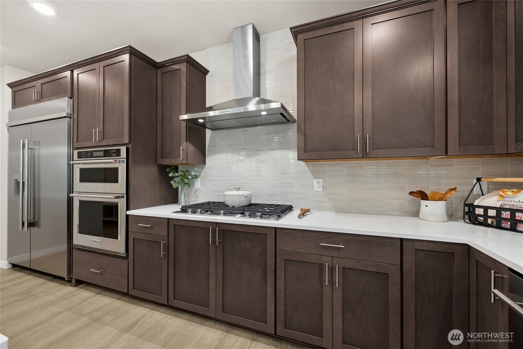 Kitchen featuring a statement hood, full height tile backsplash, and built-in gas cooktop.