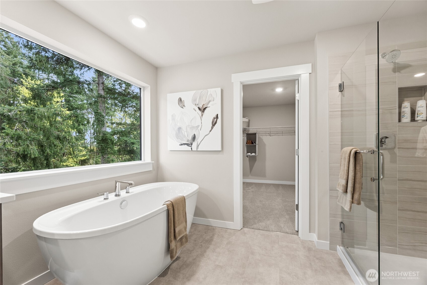 Primary bath with large picture window, glass shower and walk-in closet access.