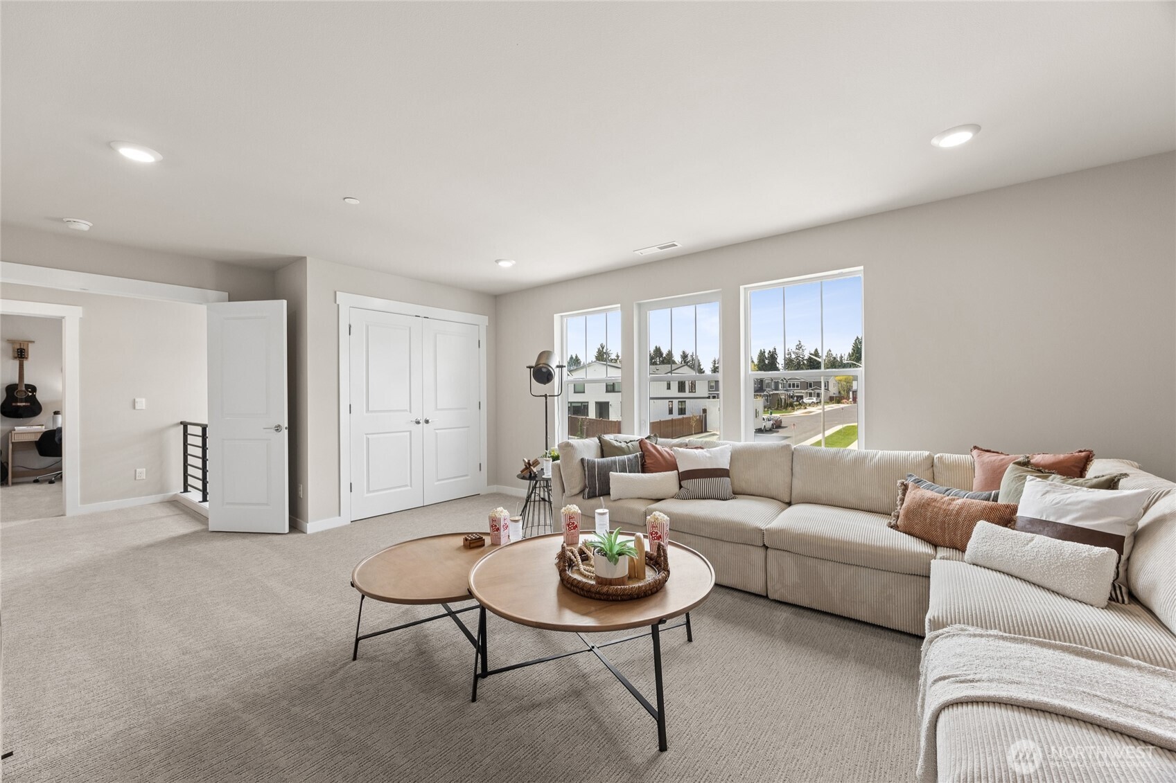 Bright upper-level living space with large windows and neighborhood views.