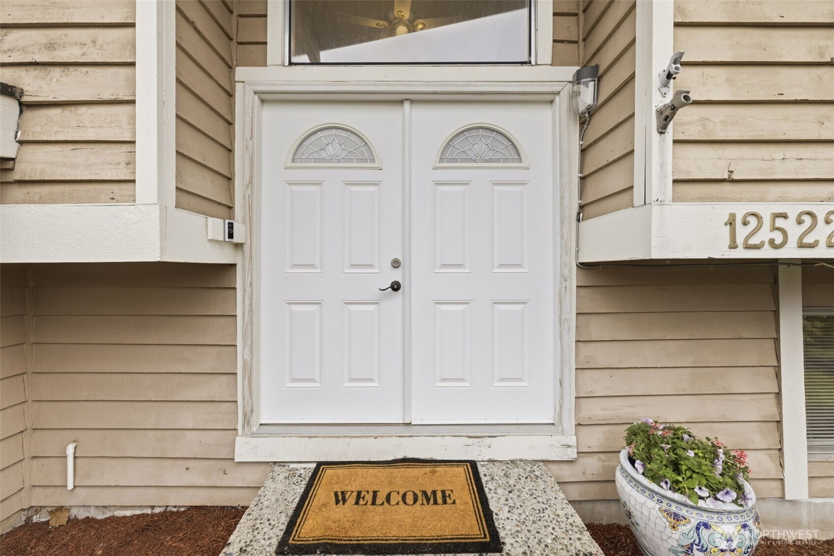 Welcoming double-door entry with transform window and covered approach.