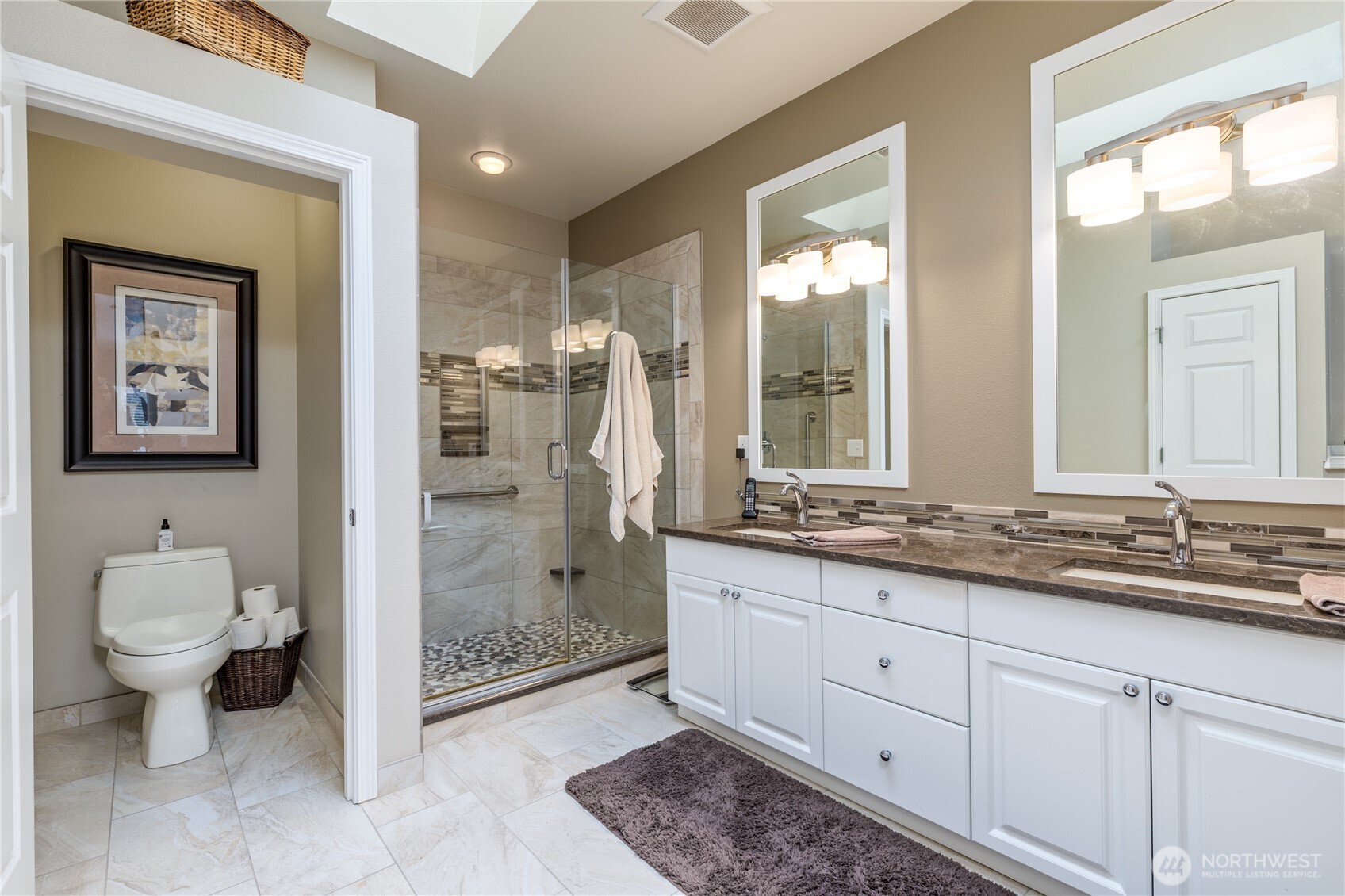 Beautifully updated primary bath featuring dual sinks, modern cabinetry, and a bright skylight