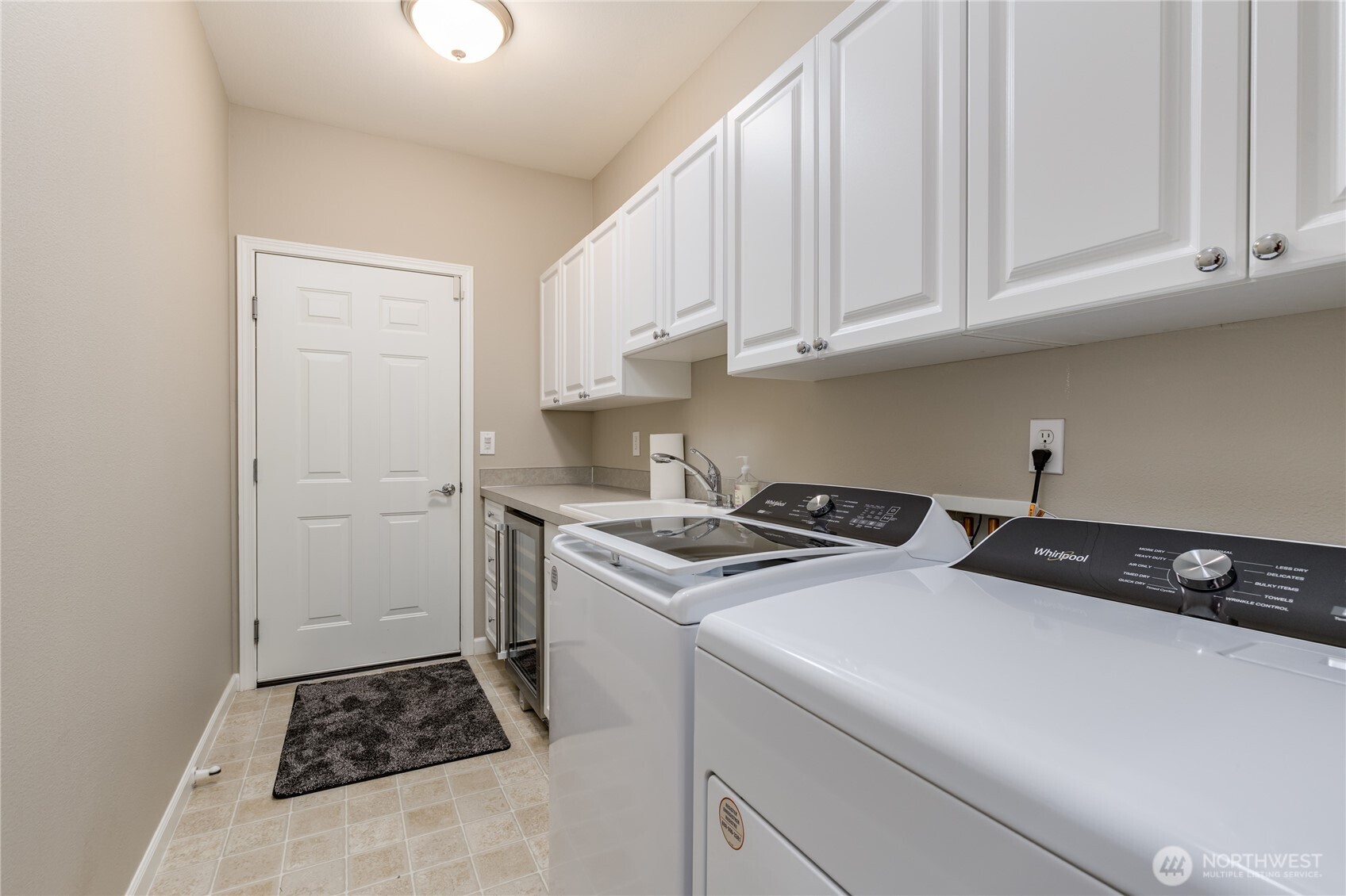 Laundry/mudroom includes utility sink, built-in cabinetry, and a beverage fridge. All appliances stay!