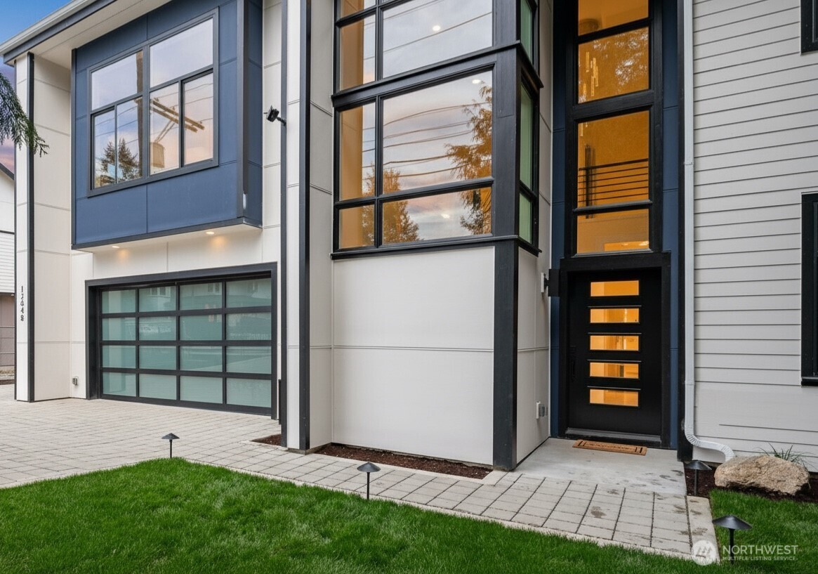 Bold modern entry with floor-to-ceiling windows, sleek lines, and glass paneled garage creating a bright and sophisticated first impression.