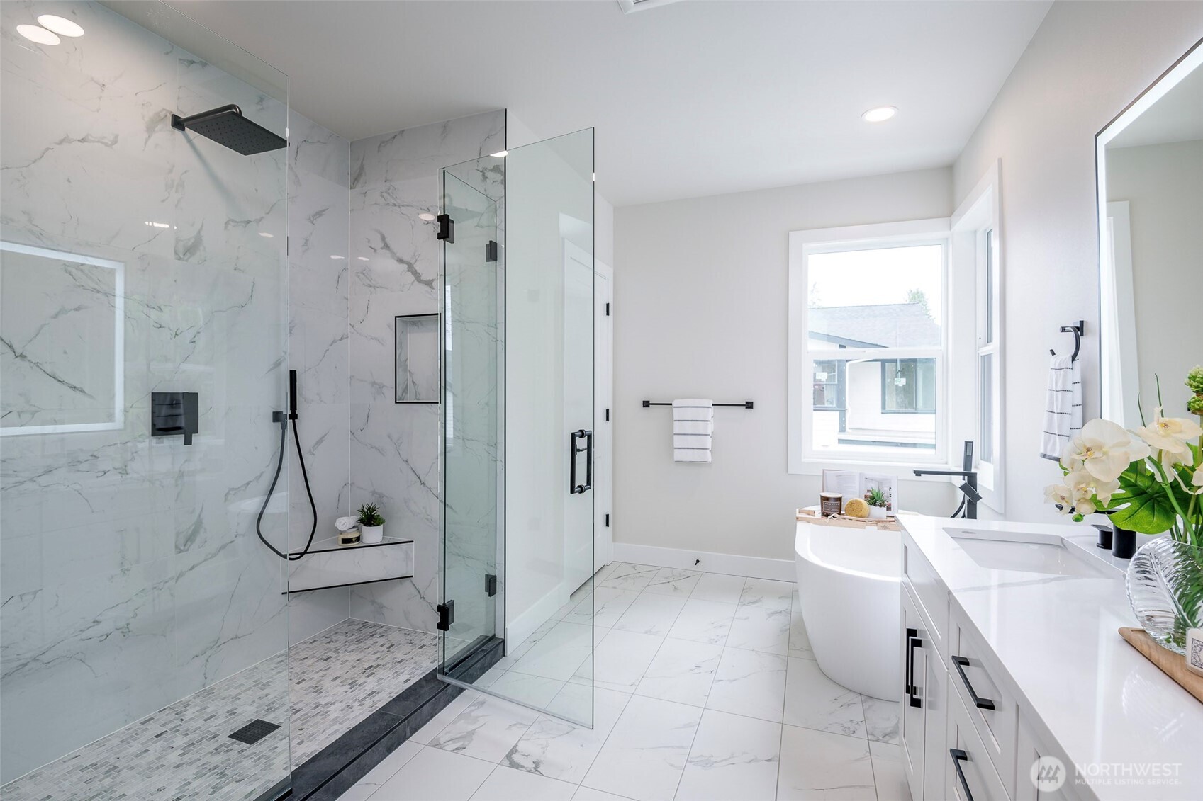 Shower features Rainfall head, wrapped in floor to ceiling tile and completed with convenient bench.