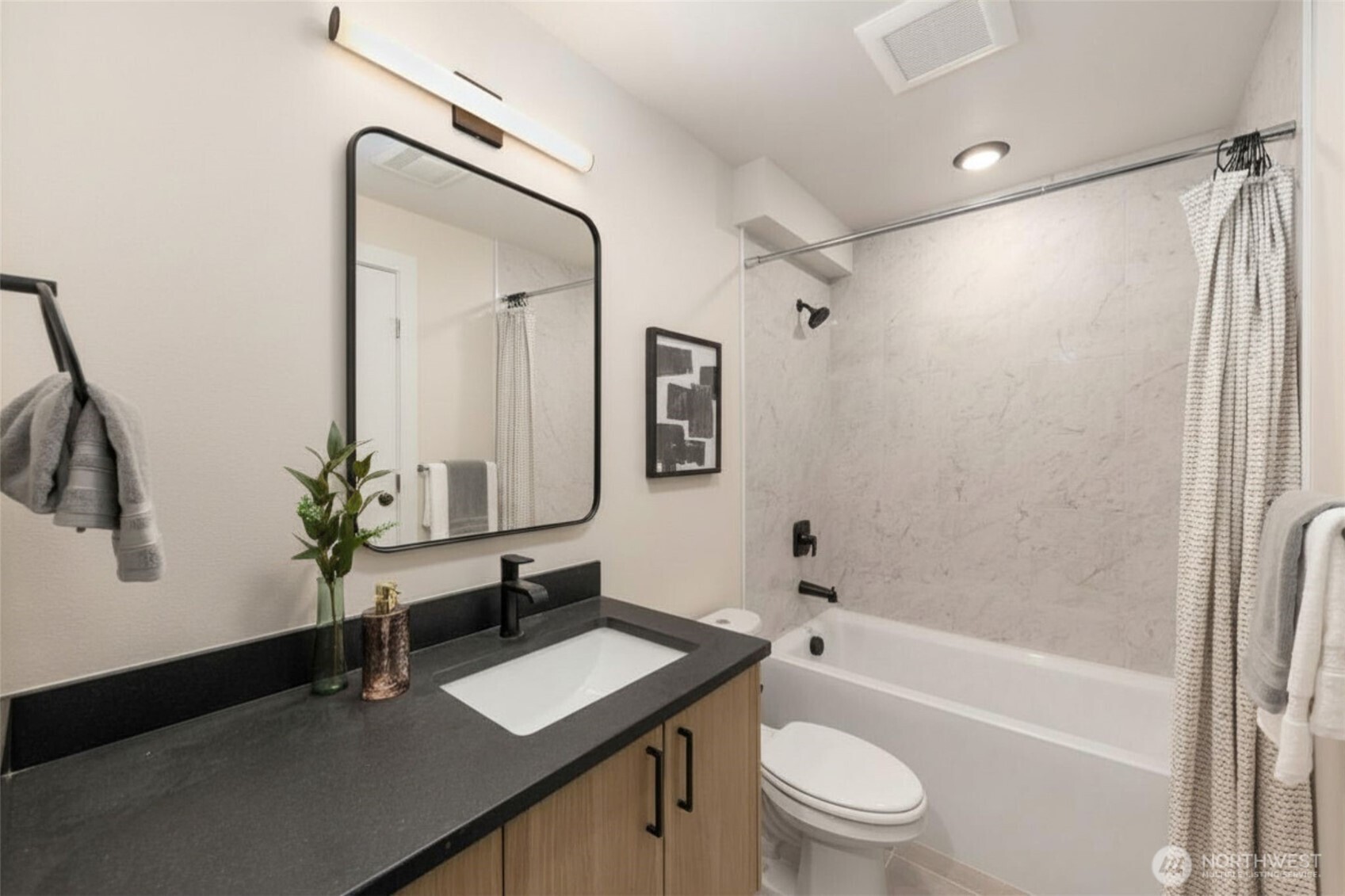 Matte black finishes, designer fixtures, and a floating vanity create a crisp, contemporary feel.