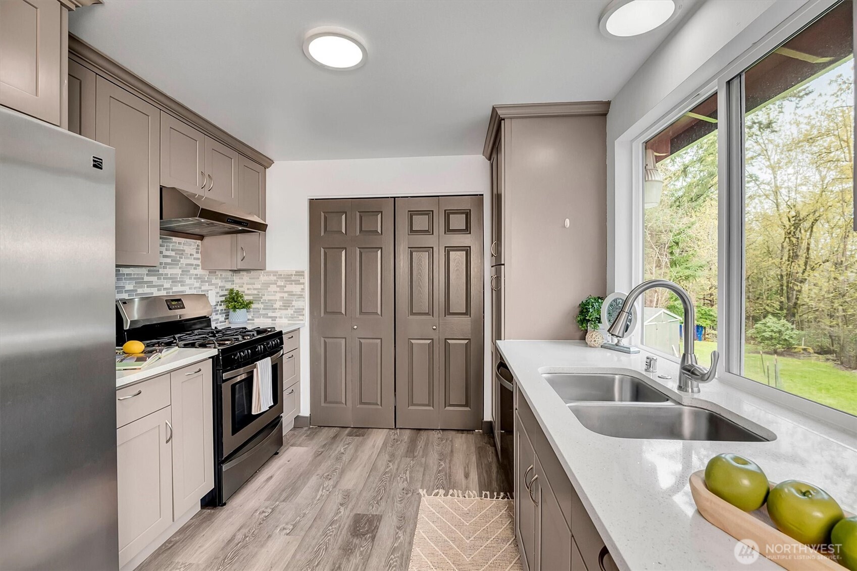 The updated kitchen shines with sleek quartz countertops, solid shaker cabinetry, gas cooktop and a picturesque window overlooking the expansive backyard.
