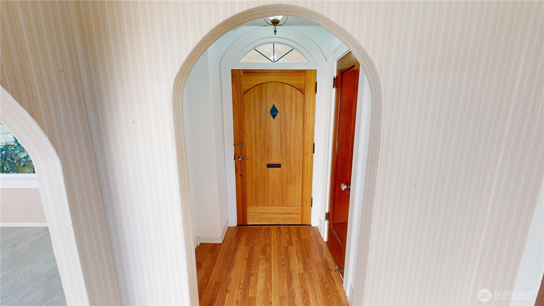 The entry way, with sweet eyebrow window, is beautifully enhanced with arches and mahogany doors.