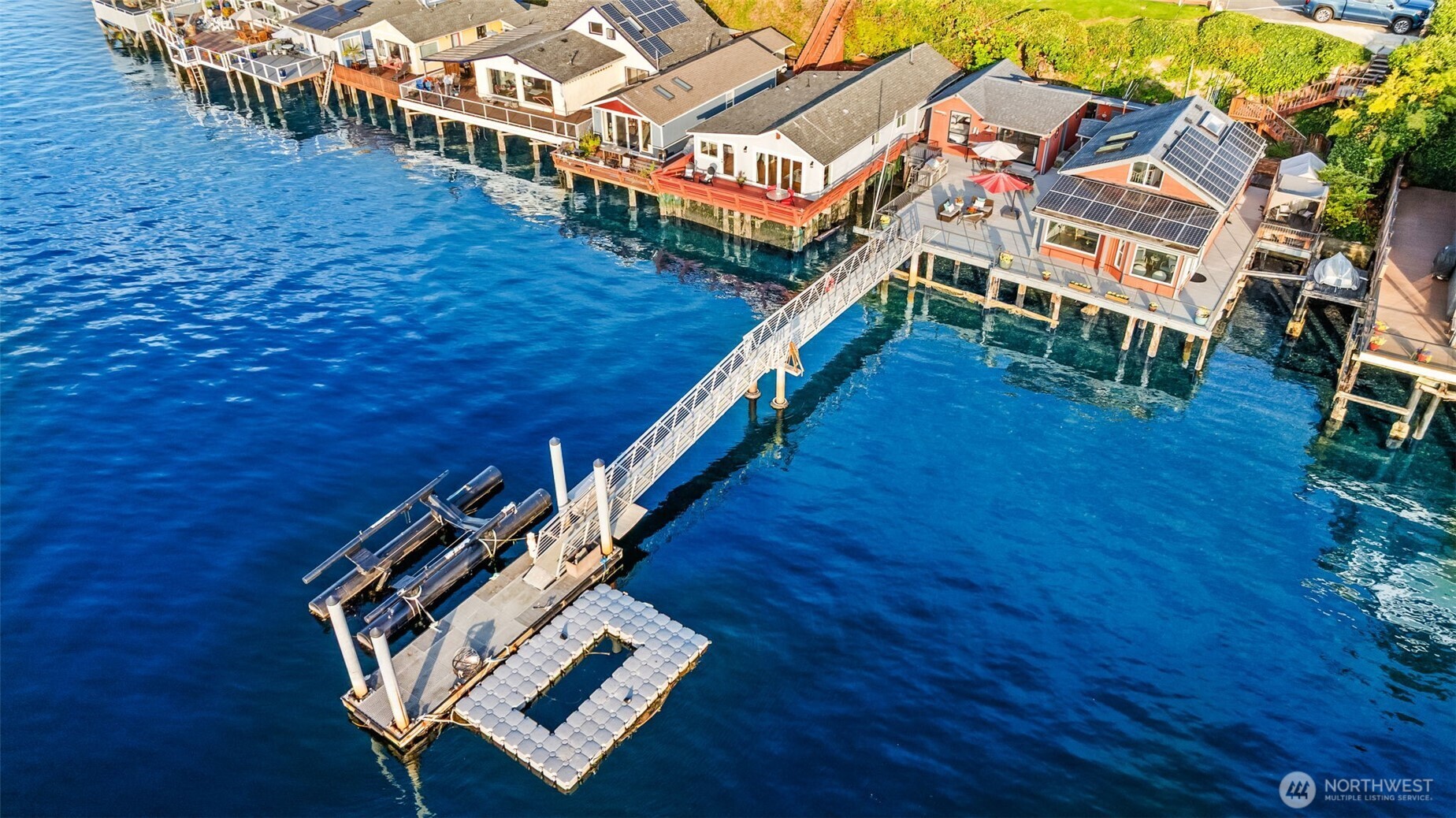 Aerial view of the property – three abodes, expansive decks, and rare deep-water dock.