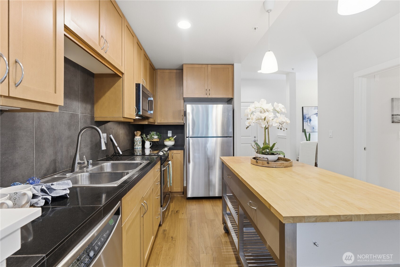 Detailed kitchen shot highlighting the stainless sink, ample cabinetry, and central island with open shelving