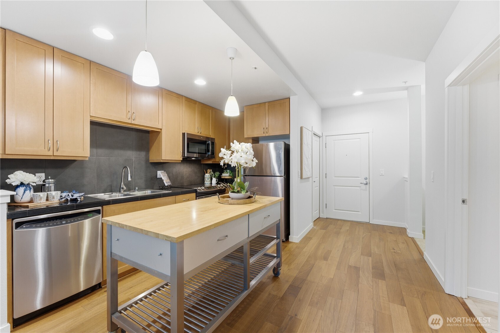 Full kitchen overview featuring warm cabinetry, stainless appliances, and a central island with pendant lighting