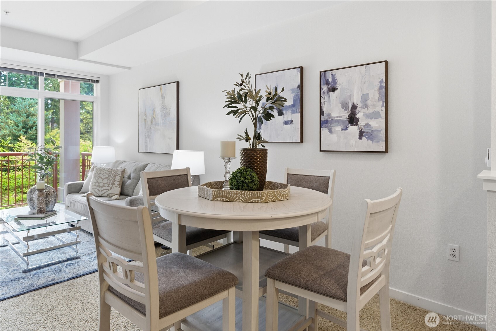 Bright dining area flowing into the comfortable living room, with large windows framing the greenery outside