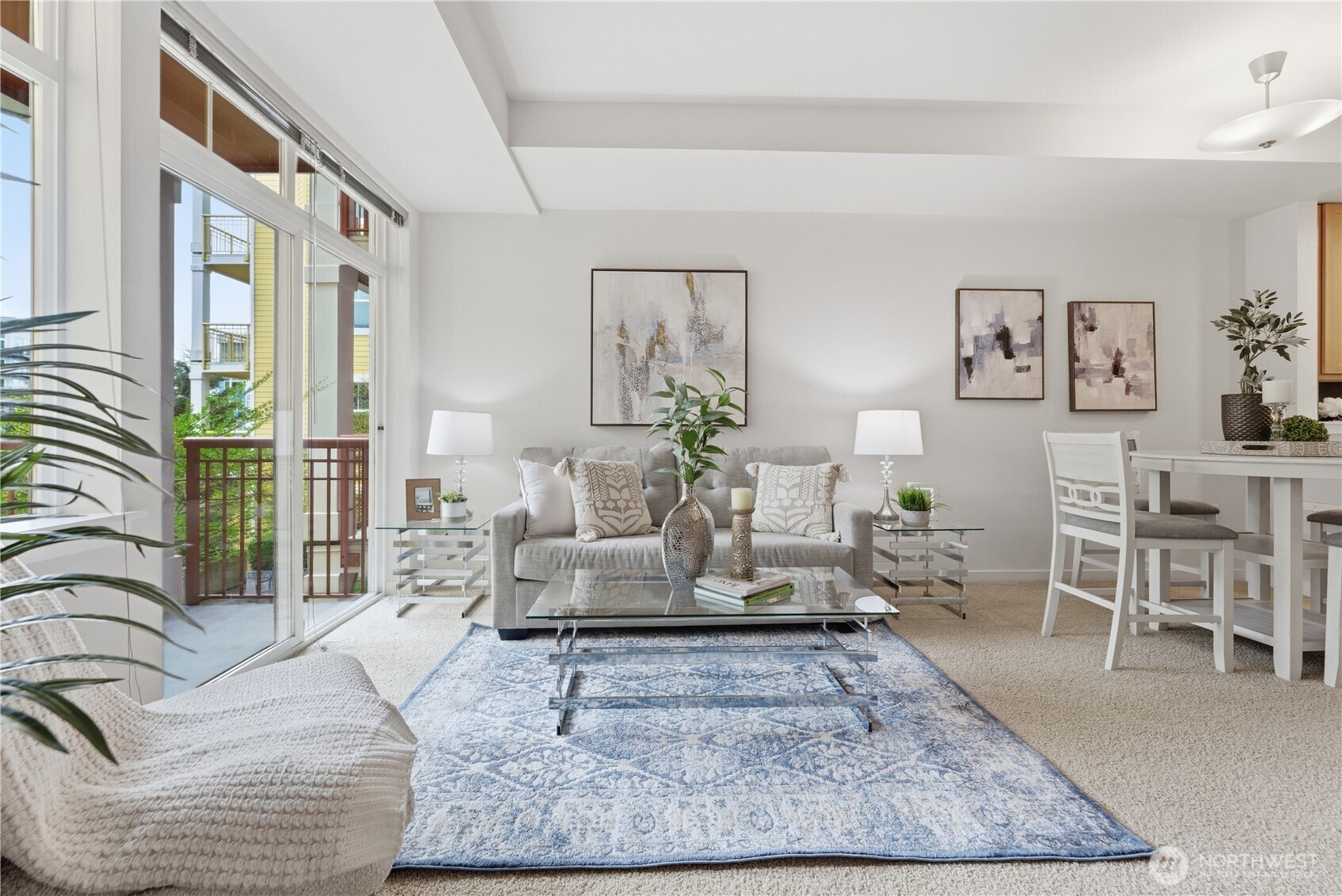 Light-filled living room where soft textures meet a wall of windows leading out to the balcony and greenery