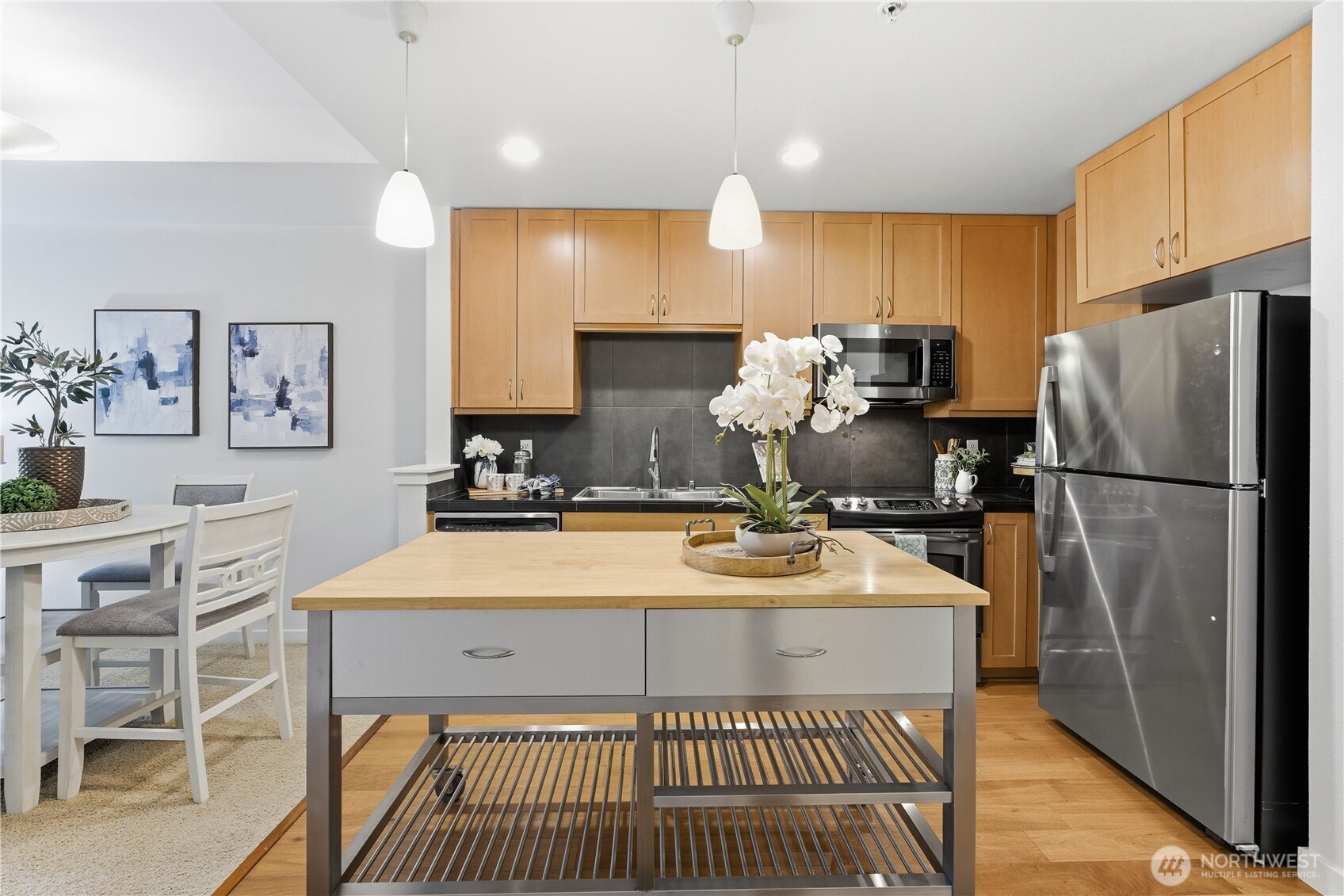 Bright, open layout with the kitchen to the right — warm finishes, stainless appliances, and an island that anchors the space
