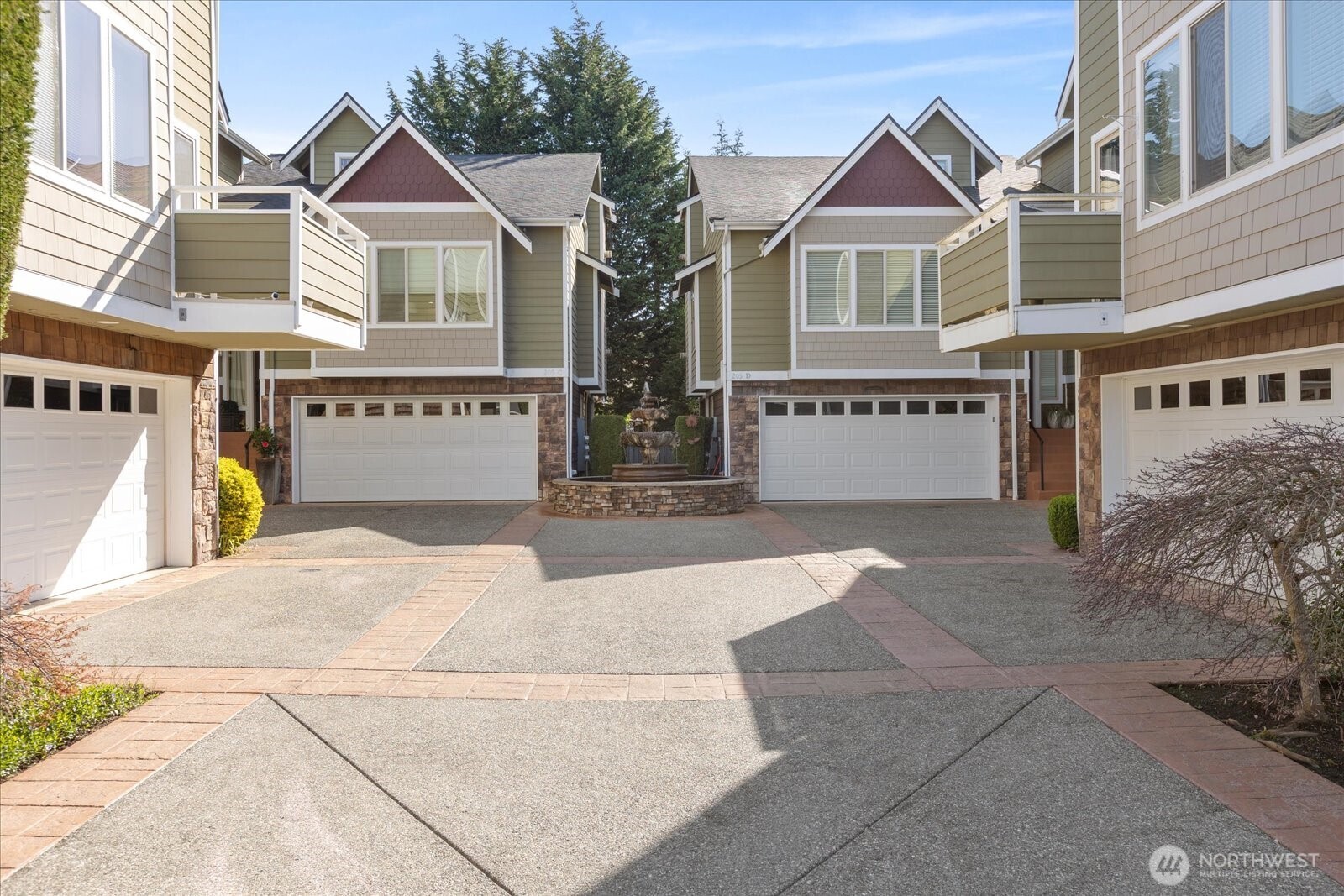 Central courtyard area with paved walkways, fountain, and multiple townhomes with balconies and garages.