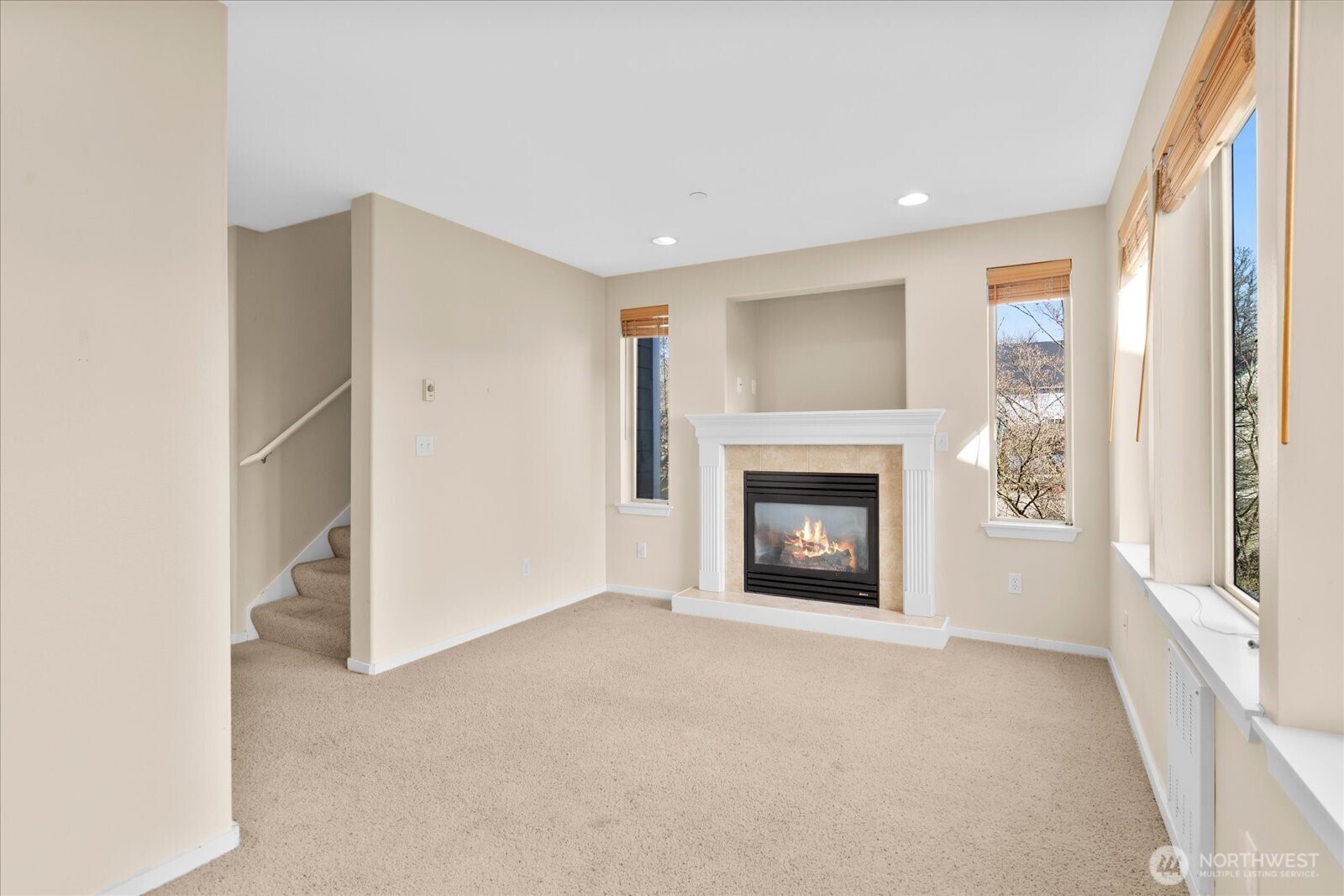 Living room featuring a gas fireplace, tall windows with blinds, recessed lighting, and carpeted flooring.