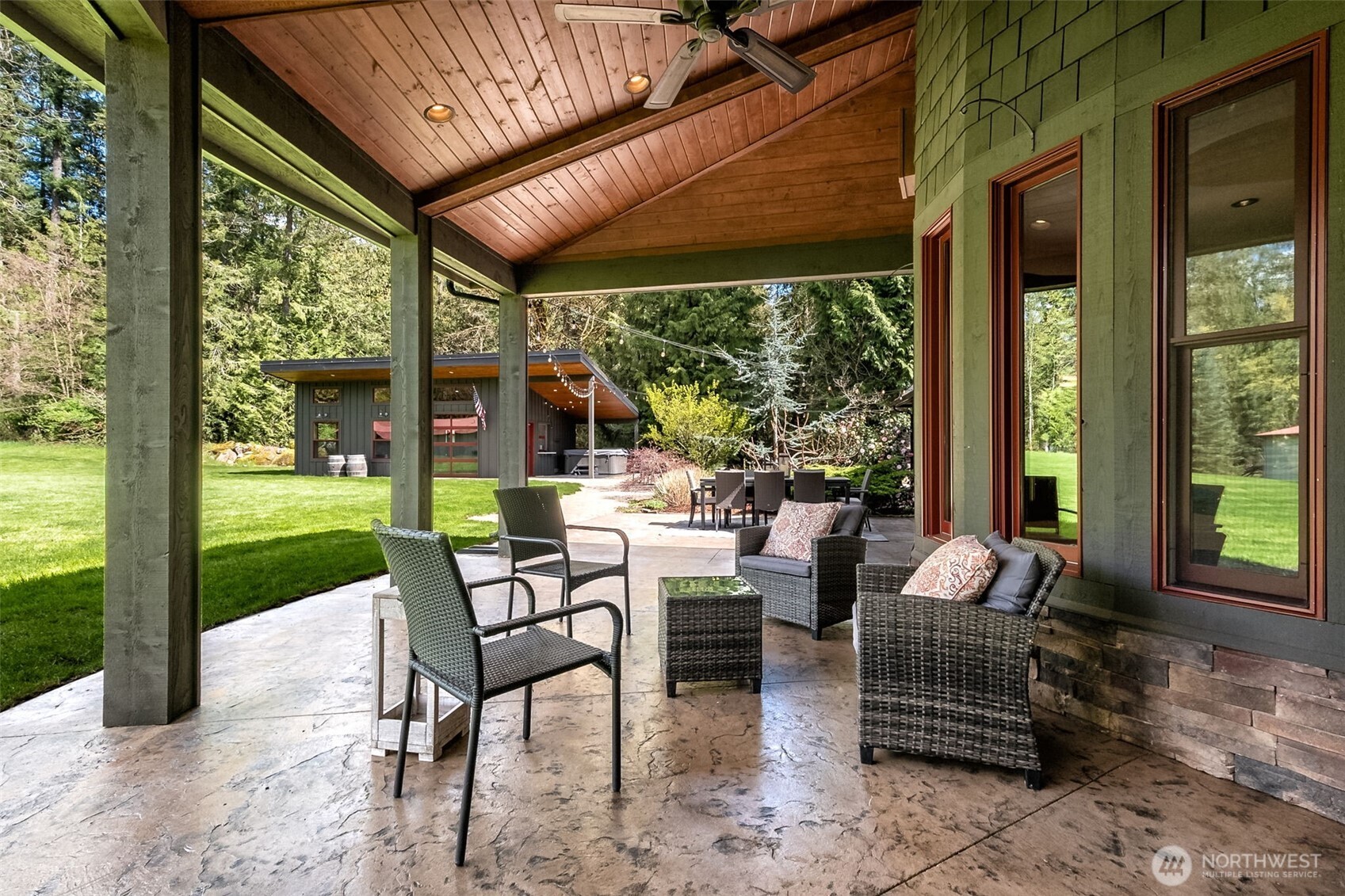 Step outside the family room for a covered patio designed for year-round enjoyment. The expansive covered patio showcases a warm wood-paneled ceiling with overhead fan, generous seating areas, and a seamless flow to the surrounding landscape—perfect for relaxing or entertaining in any season.