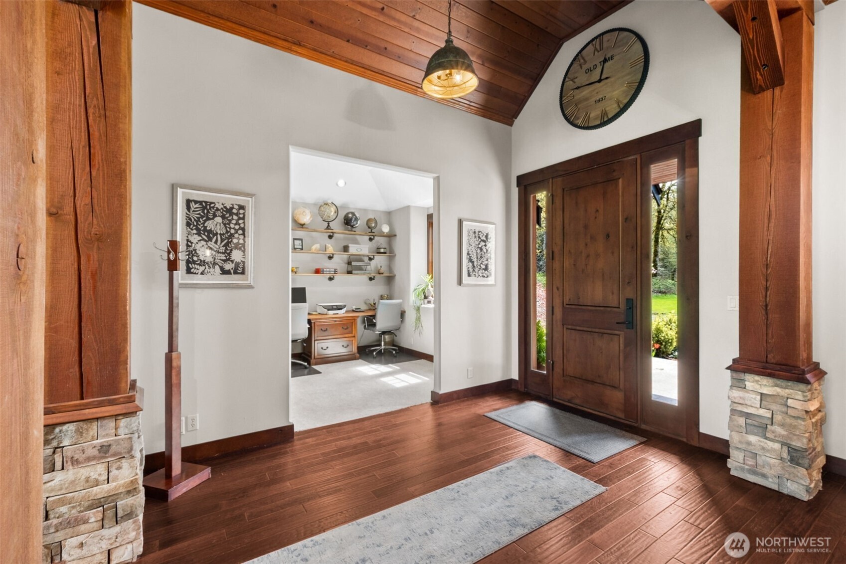 A striking entry welcomes you with a soaring wood-paneled ceiling, rich hardwood floors, and a substantial wood front door flanked by sidelights—filling the space with natural light and setting a warm, refined tone from the moment you arrive.