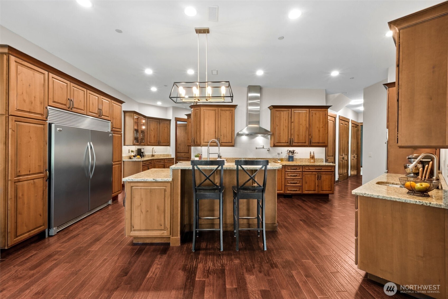 Designed with the cook in mind, the spacious kitchen offers extensive cabinetry, sprawling countertops, and a substantial center island with bar seating. Stainless steel appliances, a professional-style range hood, and thoughtful layout make it ideal for everyday living and entertaining alike.