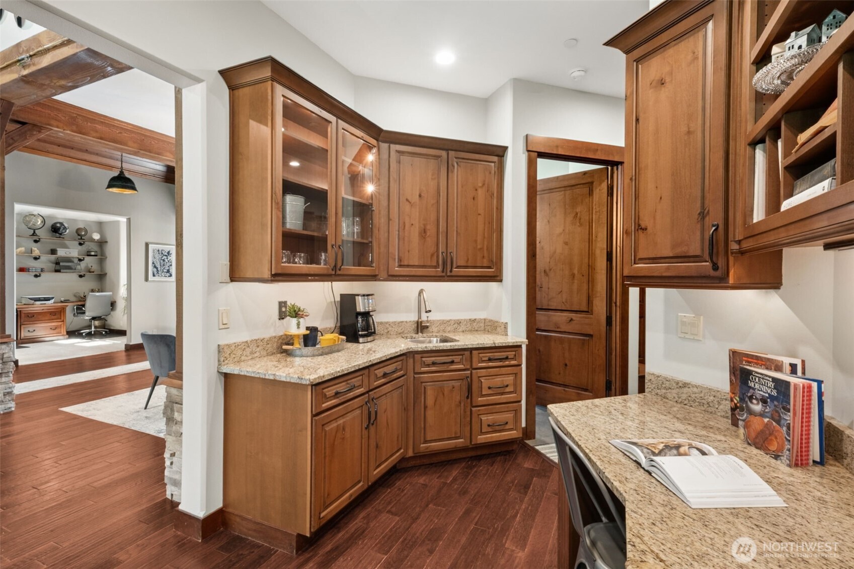 Just off the main living areas, a thoughtfully designed wet bar and command center offers granite surfaces, ample cabinetry, and a prep sink—ideal for morning coffee, homework station, or hosting with ease.