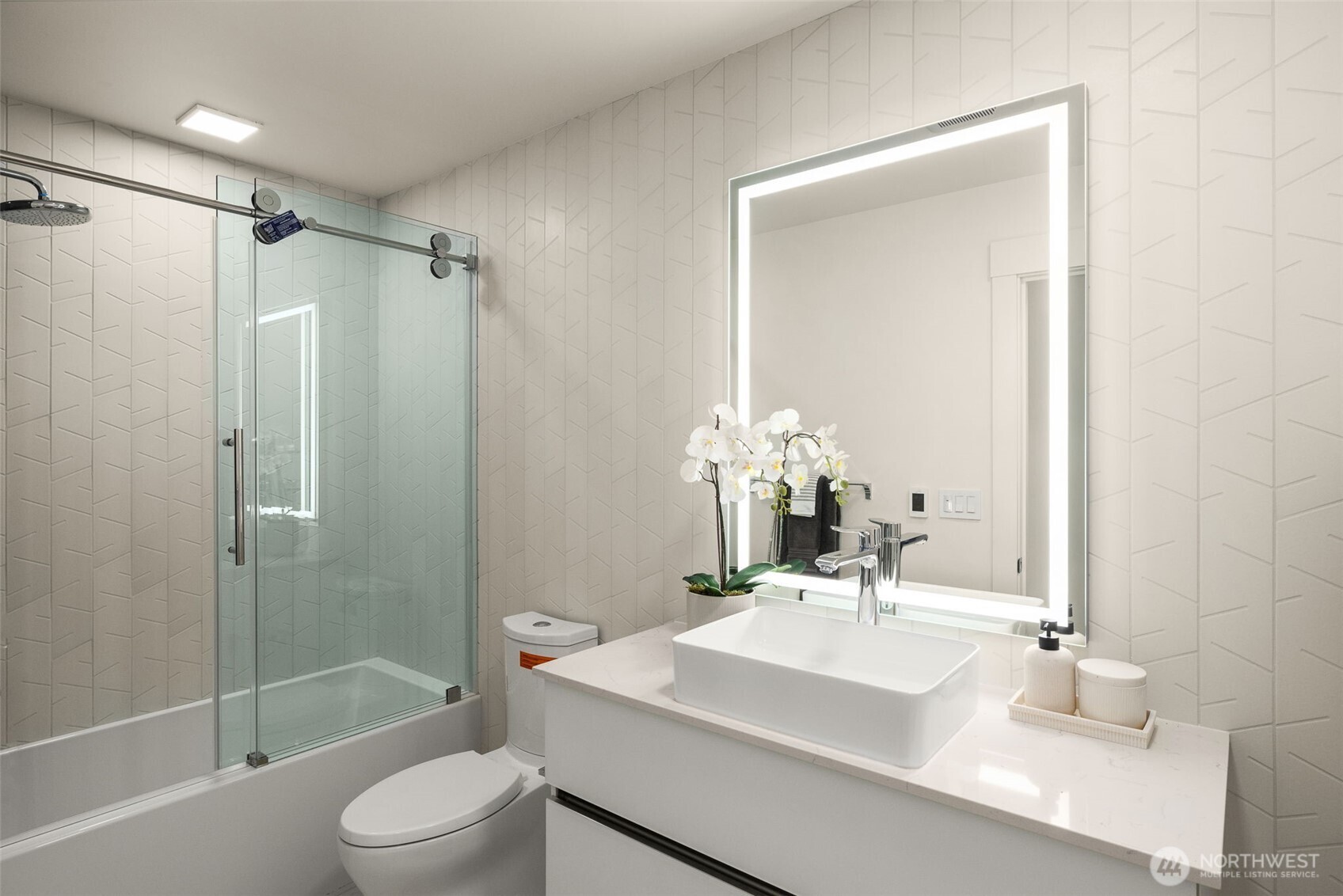 Secondary bath features heated flooring, smart anti-fog daylight mirror and a tub with ceramic tile.