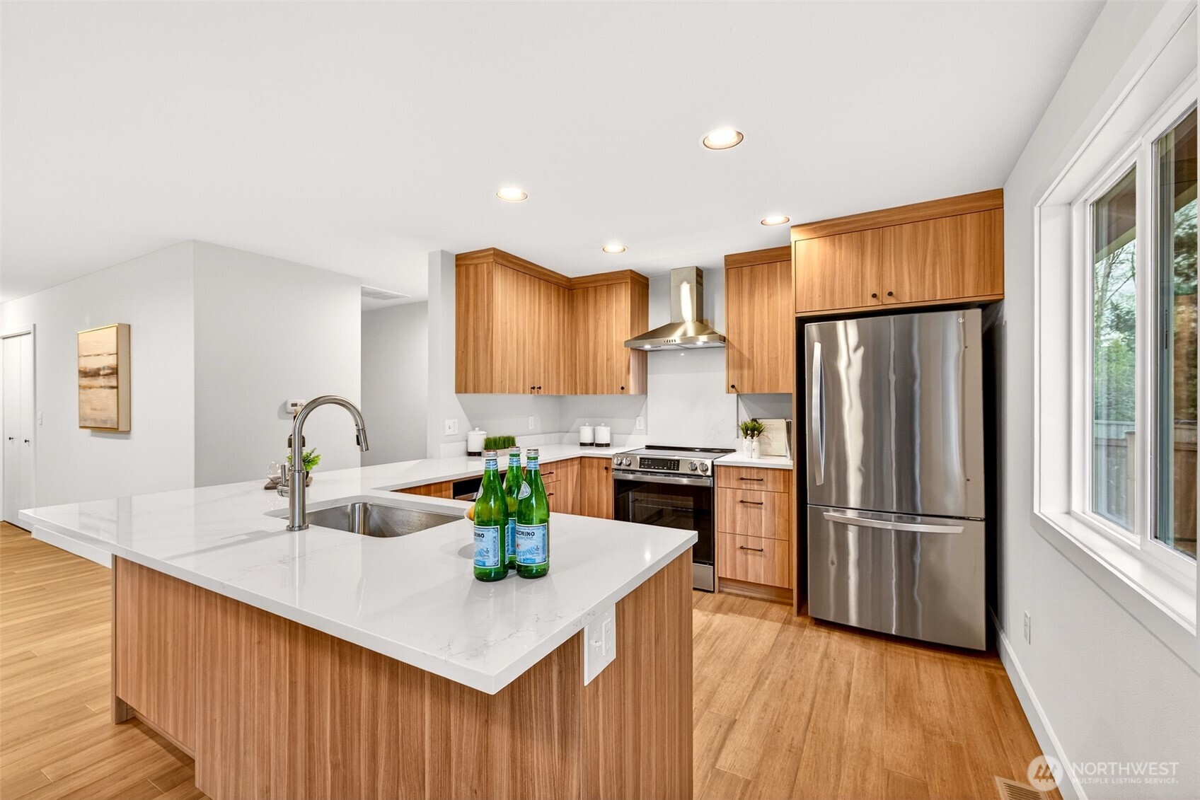 The 2026 kitchen remodel delivers a true chef's workspace, with a professional-grade stainless range, wall-mounted chimney hood, and custom walnut-tone cabinetry extending from counter height all the way to the ceiling for exceptional storage. The generous quartz peninsula with undermount sink and hardwood floors completes a kitchen that feels both high-end and highly functional.